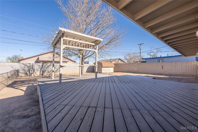 deck with a fenced backyard, an outdoor structure, and a shed