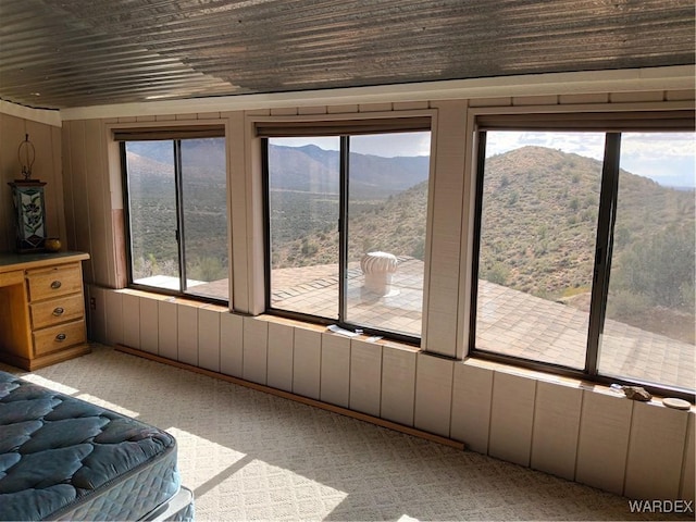 unfurnished bedroom with access to outside, multiple windows, a mountain view, and light colored carpet