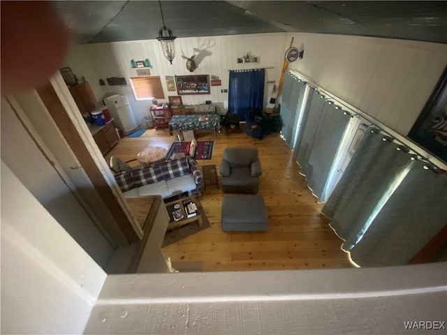 living area featuring wooden walls, vaulted ceiling, and wood finished floors