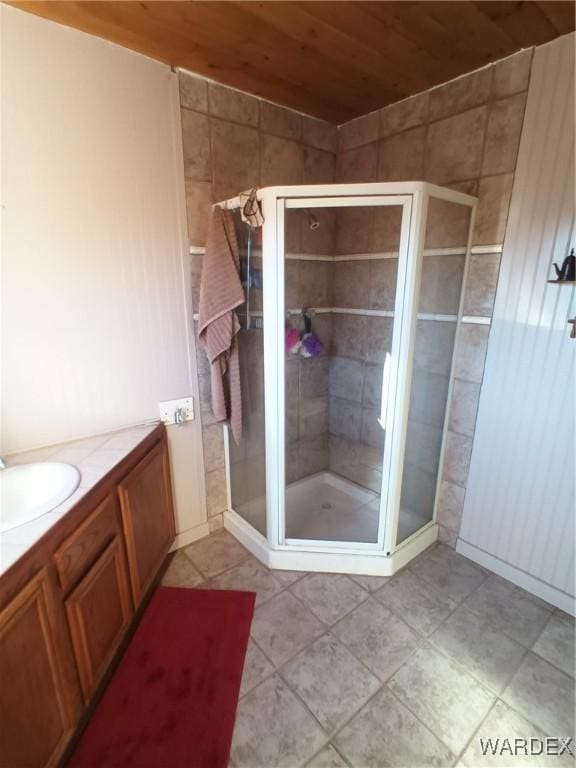 full bath featuring a stall shower, tile patterned flooring, wood ceiling, and vanity