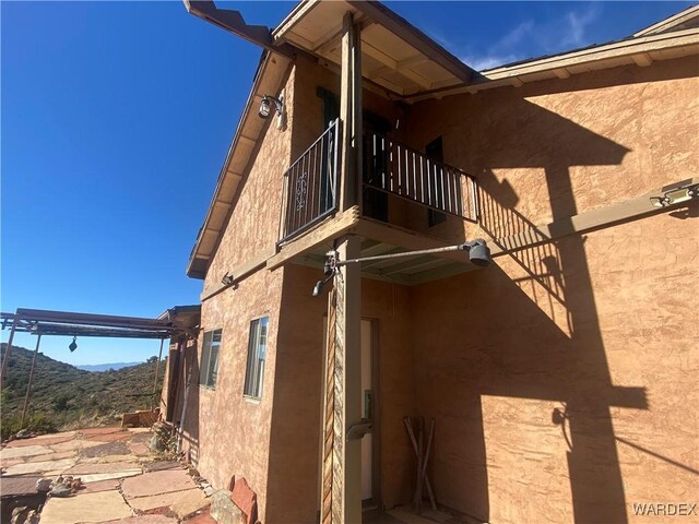 view of side of property featuring a balcony, a mountain view, and stucco siding