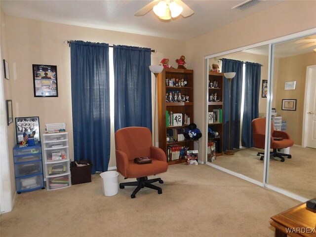 sitting room featuring a ceiling fan, visible vents, and carpet flooring