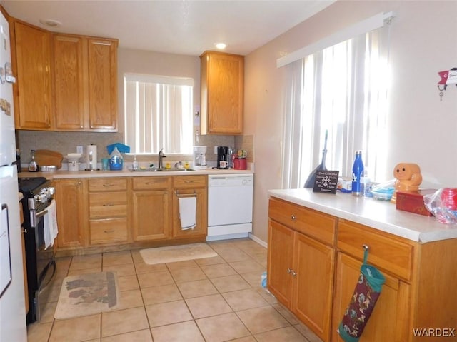 kitchen with dishwasher, gas range, backsplash, light countertops, and a sink