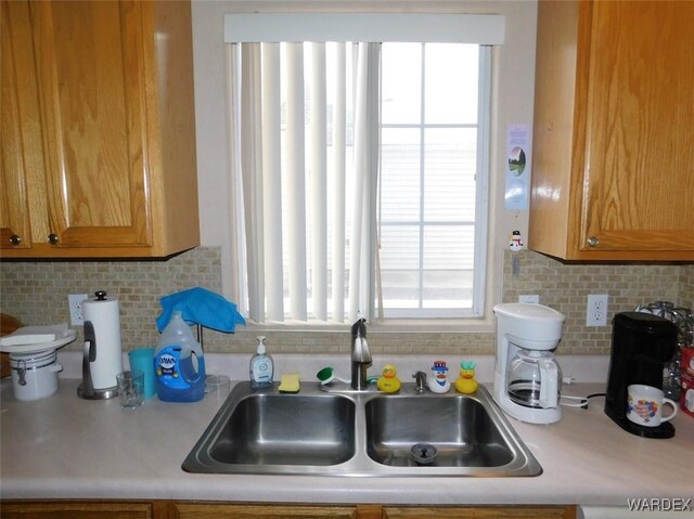 kitchen with plenty of natural light, light countertops, a sink, and decorative backsplash