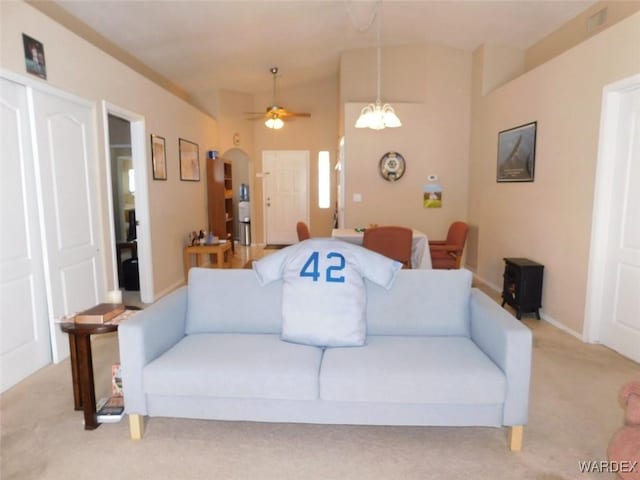 living room with arched walkways, light carpet, baseboards, and ceiling fan with notable chandelier