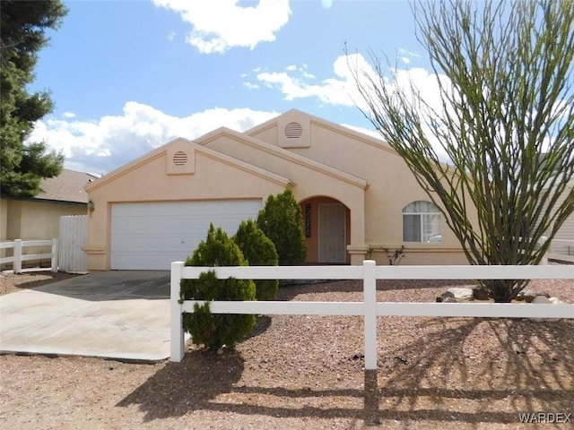 view of front of property with a fenced front yard, concrete driveway, an attached garage, and stucco siding