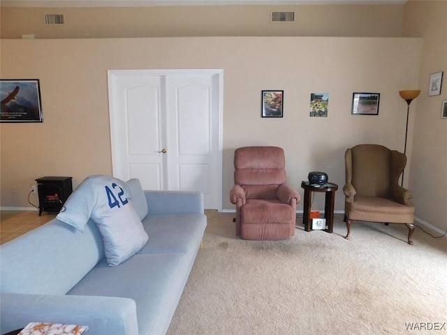 carpeted living area featuring a wood stove, visible vents, and baseboards