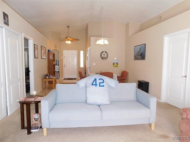 living room featuring light colored carpet, visible vents, and ceiling fan with notable chandelier