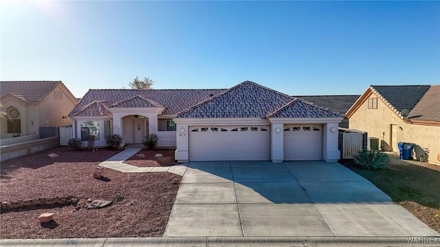 view of front of home featuring an attached garage, cooling unit, a tiled roof, concrete driveway, and stucco siding