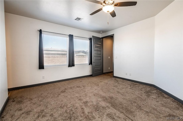 carpeted spare room with visible vents, baseboards, and ceiling fan