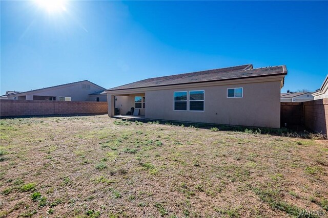 back of house with a yard, a fenced backyard, a patio area, and stucco siding