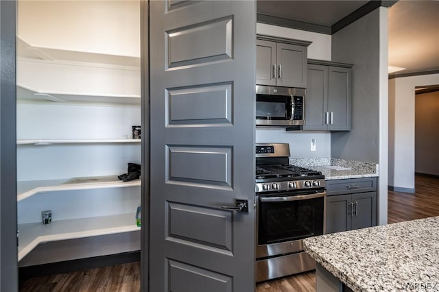 kitchen with dark wood-style floors, appliances with stainless steel finishes, gray cabinets, and light stone counters