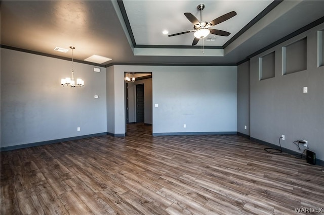 empty room with ceiling fan with notable chandelier, ornamental molding, a tray ceiling, and wood finished floors