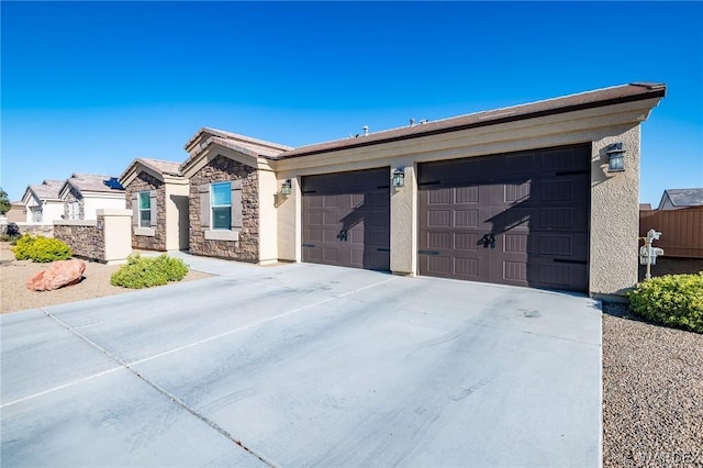 view of front of house featuring a garage, concrete driveway, stone siding, and stucco siding