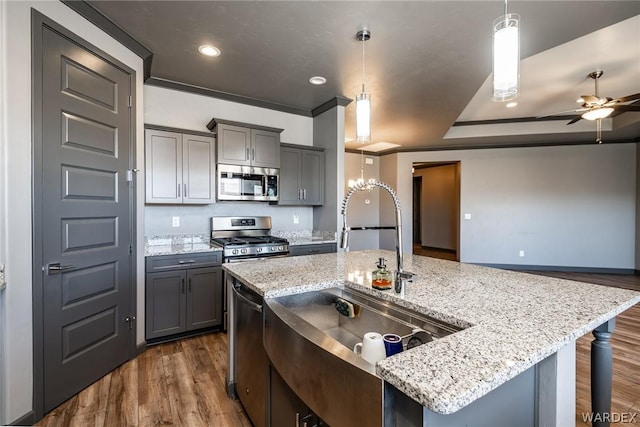 kitchen featuring hanging light fixtures, gray cabinets, stainless steel appliances, and an island with sink