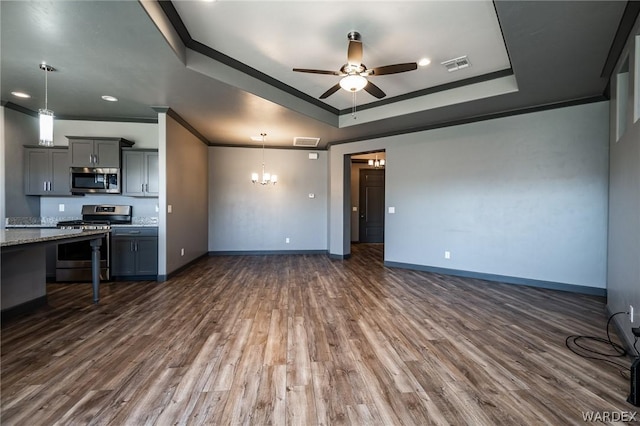 unfurnished living room with ornamental molding, a tray ceiling, dark wood-style floors, and visible vents