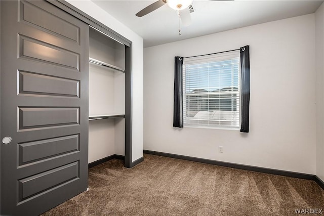 unfurnished bedroom featuring dark colored carpet, a closet, a ceiling fan, and baseboards