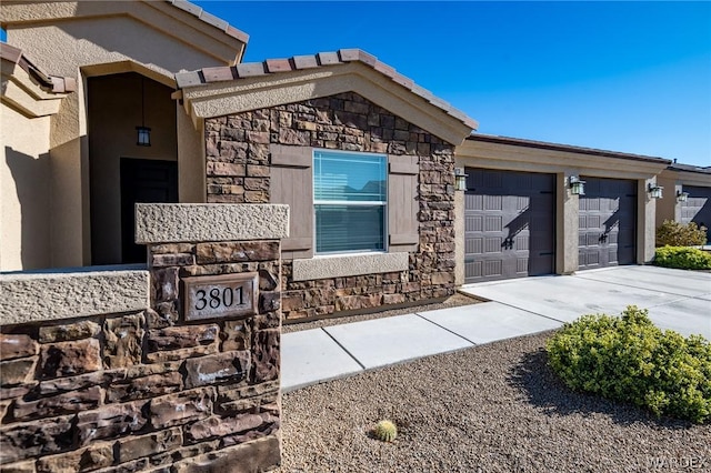 property entrance featuring a garage, stone siding, and driveway