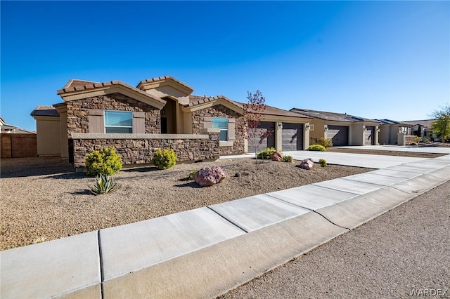 view of front facade featuring a tile roof, stucco siding, an attached garage, stone siding, and driveway