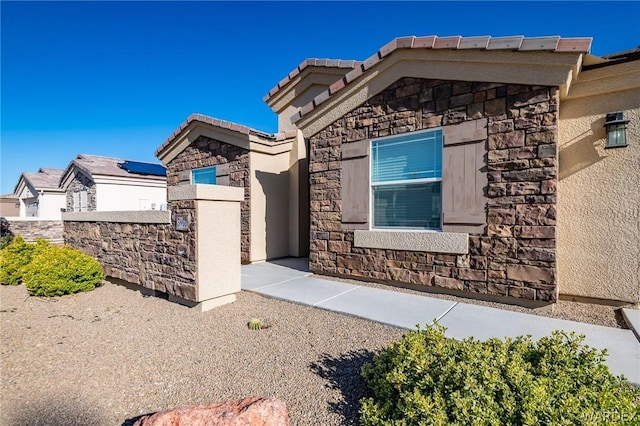 view of front facade featuring stone siding, stucco siding, and a tiled roof