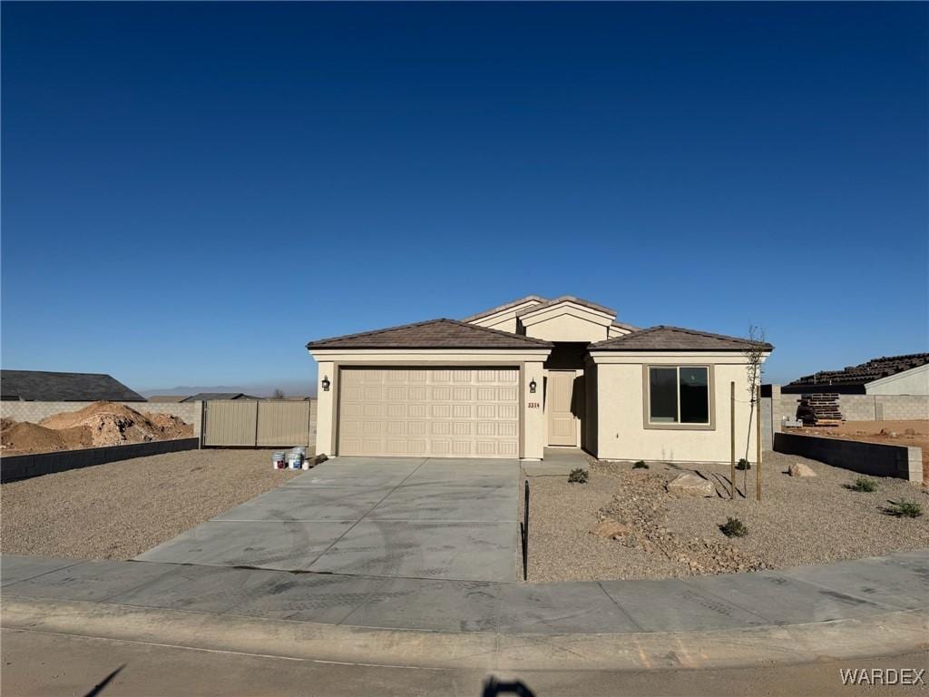 view of front of home with concrete driveway, fence, a garage, and stucco siding