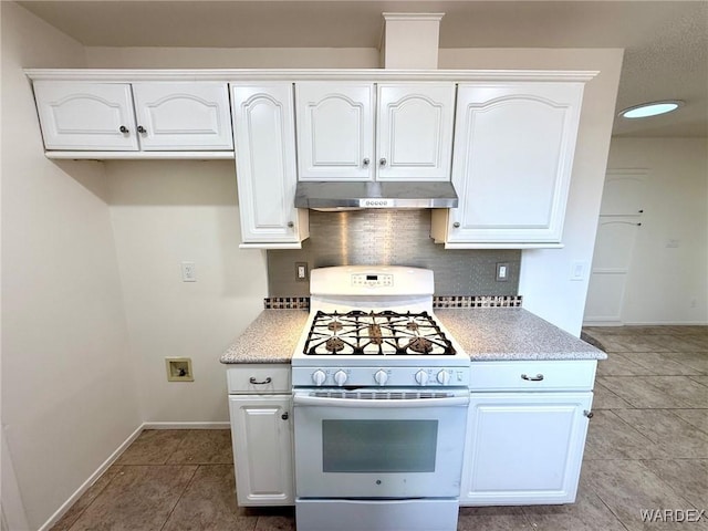 kitchen with light tile patterned floors, under cabinet range hood, white cabinets, white range with gas cooktop, and tasteful backsplash