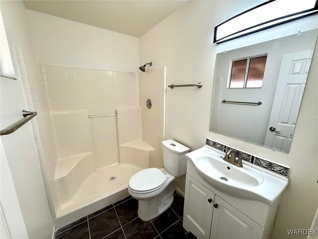 full bath featuring tile patterned flooring, tiled shower, vanity, and toilet