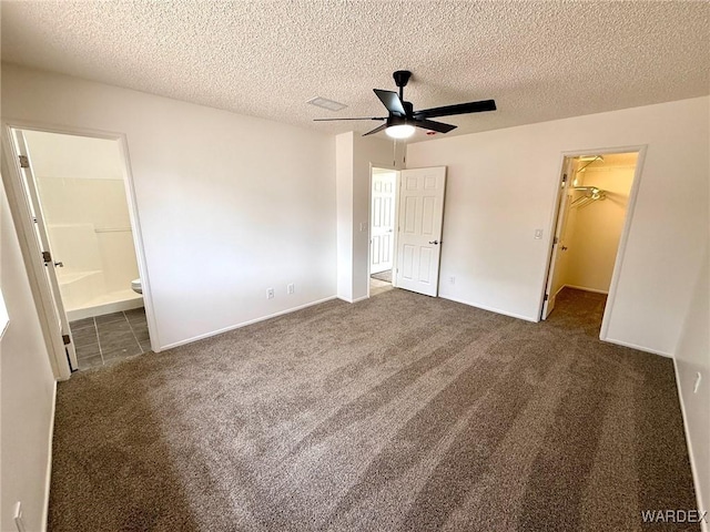 unfurnished bedroom with a textured ceiling, connected bathroom, a spacious closet, a closet, and carpet