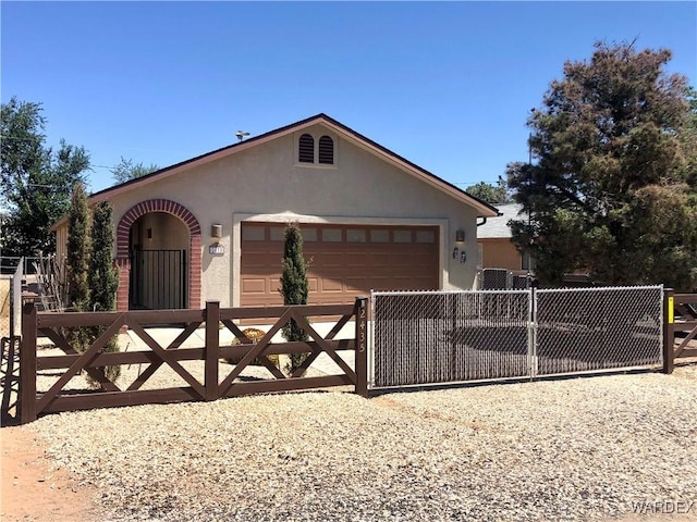 view of front of property with an attached garage, a fenced front yard, a gate, and stucco siding