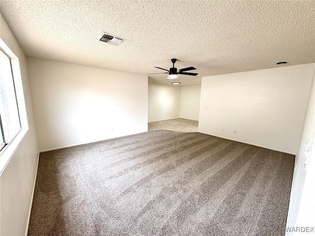 spare room featuring ceiling fan, carpet floors, a textured ceiling, and visible vents