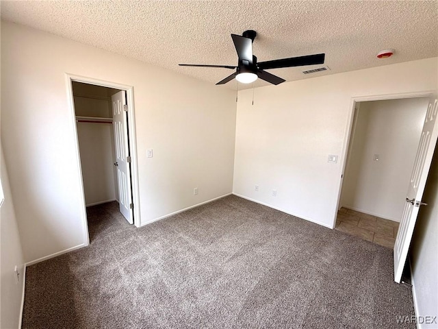 unfurnished bedroom with visible vents, a ceiling fan, a spacious closet, carpet flooring, and a textured ceiling