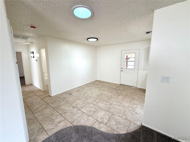 unfurnished room featuring a textured ceiling, visible vents, and baseboards