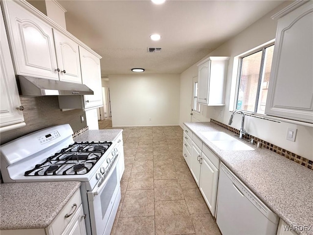 kitchen with under cabinet range hood, white appliances, a sink, white cabinets, and tasteful backsplash