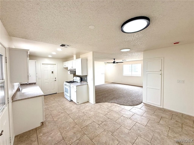 kitchen with white range with gas stovetop, visible vents, white cabinets, a ceiling fan, and light countertops