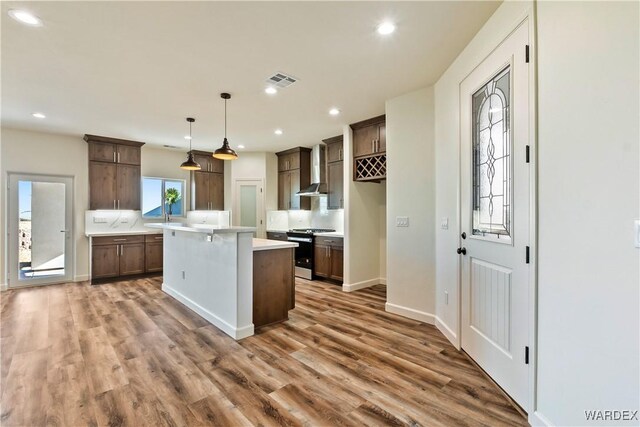 10726 S River Terrace Dr, Mohave Valley, AZ 86440 - kitchen with stainless steel range with gas cooktop, wall chimney exhaust hood, a center island, light countertops, and a sink