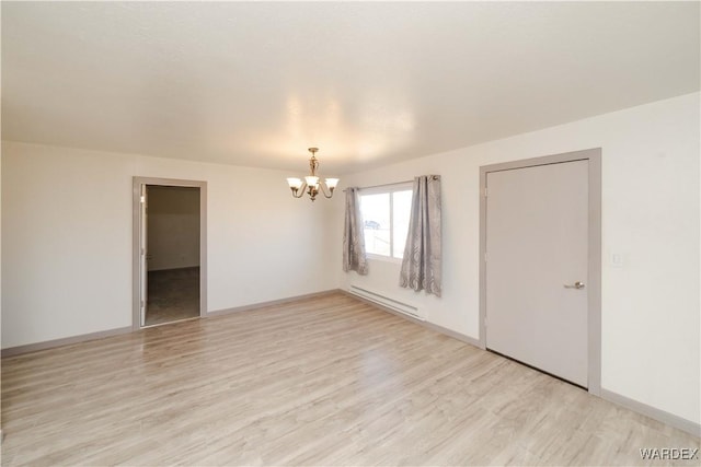 spare room featuring a baseboard heating unit, baseboards, light wood finished floors, and an inviting chandelier