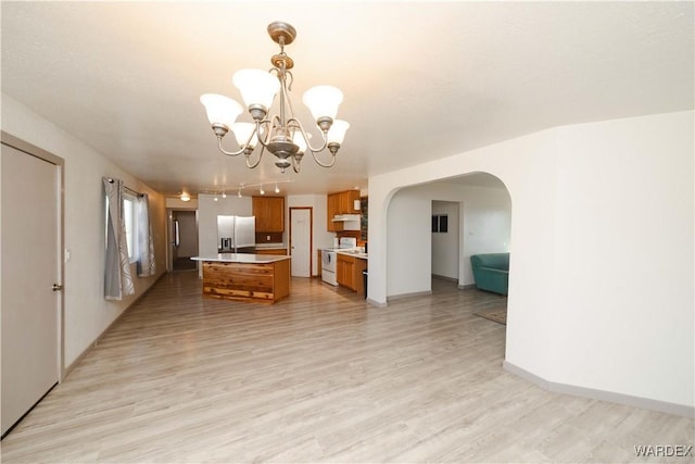 kitchen featuring electric stove, light countertops, hanging light fixtures, brown cabinetry, and a kitchen island