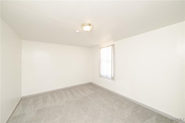 empty room featuring baseboards and light colored carpet