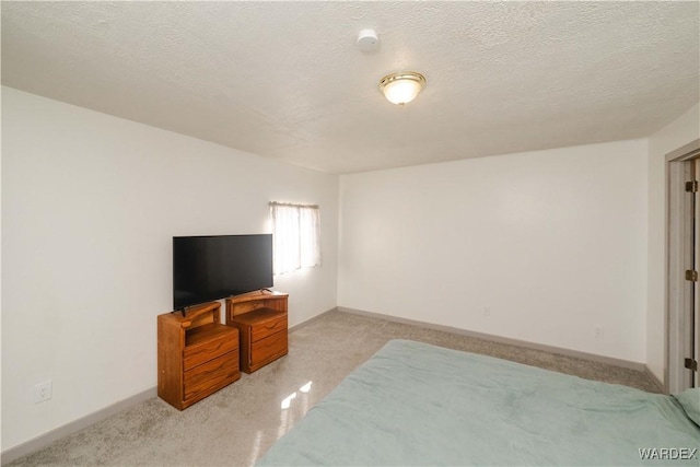 bedroom featuring a textured ceiling, baseboards, and light colored carpet