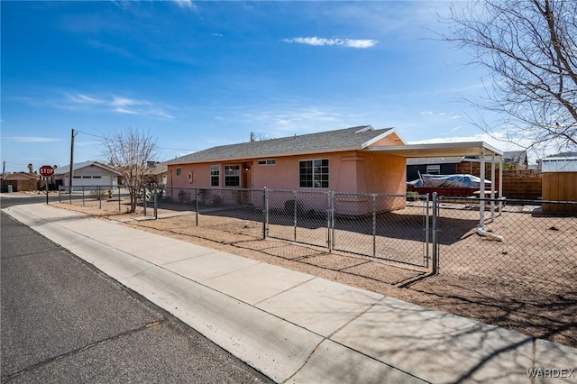 view of front facade featuring a fenced front yard, driveway, a gate, stucco siding, and a carport