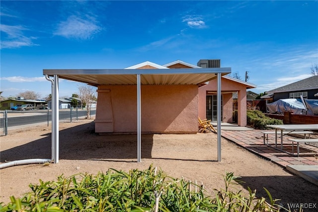 rear view of property featuring stucco siding, fence, and a patio