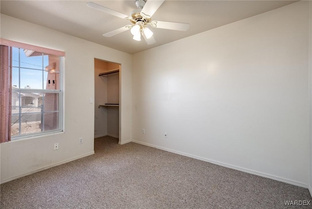 unfurnished bedroom with a walk in closet, baseboards, multiple windows, and carpet flooring