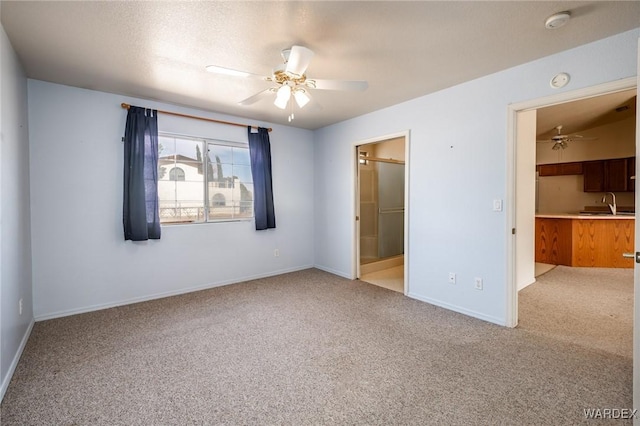 unfurnished bedroom with light colored carpet, a spacious closet, a sink, ensuite bath, and baseboards