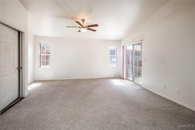 carpeted empty room with a ceiling fan and baseboards