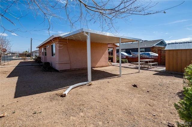 view of property exterior featuring an outbuilding, fence, a storage unit, a patio area, and stucco siding