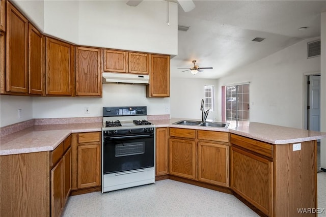 kitchen with under cabinet range hood, a peninsula, a sink, a ceiling fan, and range with gas cooktop