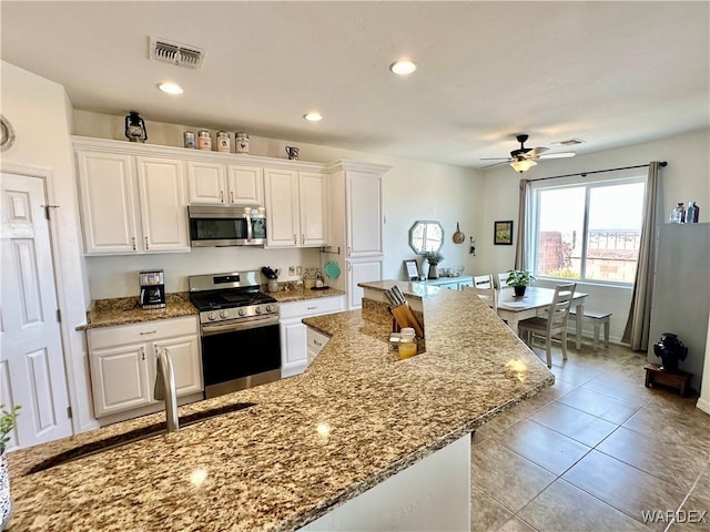 kitchen featuring light stone countertops, appliances with stainless steel finishes, white cabinetry, visible vents, and a ceiling fan