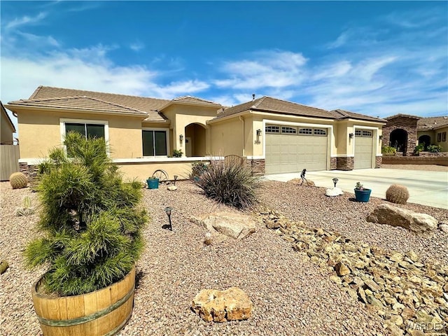 mediterranean / spanish-style home with stucco siding, fence, a garage, driveway, and stone siding