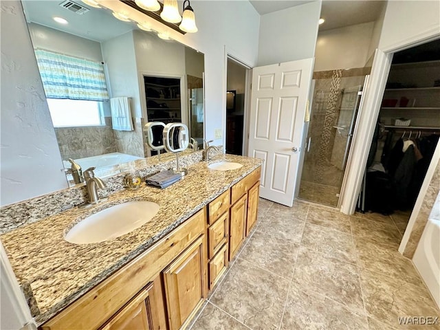 full bath featuring a walk in closet, visible vents, a bath, and a sink