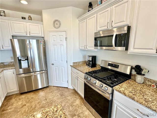 kitchen featuring white cabinets, stainless steel appliances, and light stone countertops